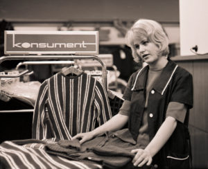 Young saleswoman in the 1968 newly opened consumer department store on Bruehl in Richard-Wagner-Strasse in the center of Leipzig. At that time the largest department store in the GDR, popularly called tin can, because of the aluminum shell of the outer facade made in honeycomb patterns, which unfortunately heated up the house very much. Young saleswoman in the 1968 newly opened consumer department store on Bruehl in Richard-Wagner-Strasse in the center of Leipzig. At that time the largest department store in the GDR, popularly called tin can, because of the aluminum shell of the outer facade made in honeycomb patterns, which unfortunately heated up the house very much.